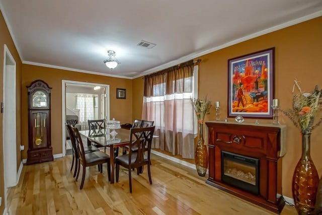 dining space featuring crown molding, light wood finished floors, baseboards, and visible vents