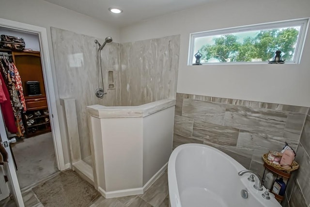 bathroom featuring a tub to relax in, a spacious closet, and a walk in shower