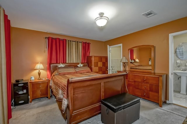 bedroom featuring a sink, visible vents, ensuite bath, and light carpet
