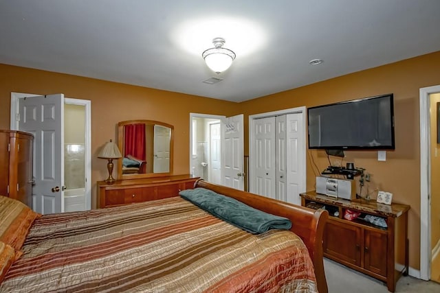 bedroom with light carpet, ensuite bath, visible vents, and a closet