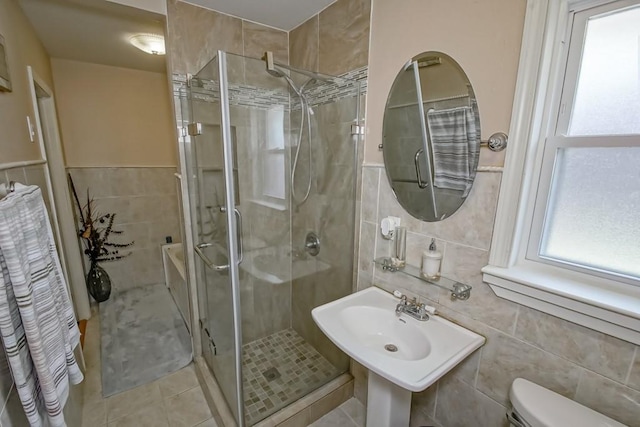 full bath with tile patterned flooring, tile walls, toilet, and a stall shower