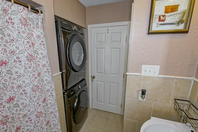 full bath with tile walls, tile patterned floors, stacked washing maching and dryer, and a shower with curtain