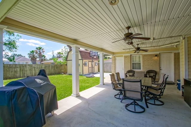 view of patio with a shed, ceiling fan, grilling area, a fenced backyard, and an outdoor structure