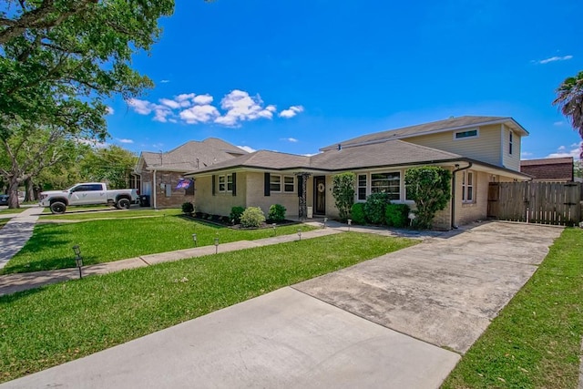 view of front of property featuring a front lawn, a gate, driveway, fence, and brick siding
