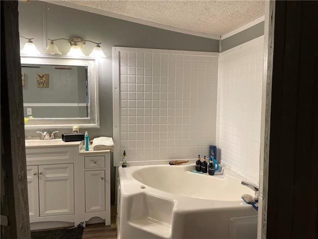 69476 S River Rd, Kentwood, LA 70444 - bathroom featuring vanity, ornamental molding, a textured ceiling, a garden tub, and wood finished floors