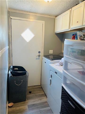 69476 S River Rd, Kentwood, LA 70444 - laundry room with light wood finished floors, washing machine and dryer, a textured ceiling, and cabinet space
