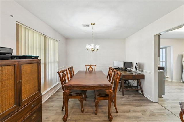 dining area featuring baseboards, light wood-type flooring, a notable chandelier, and visible vents