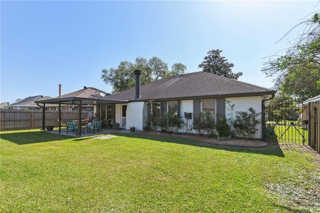 rear view of house with a yard, fence, brick siding, and a patio