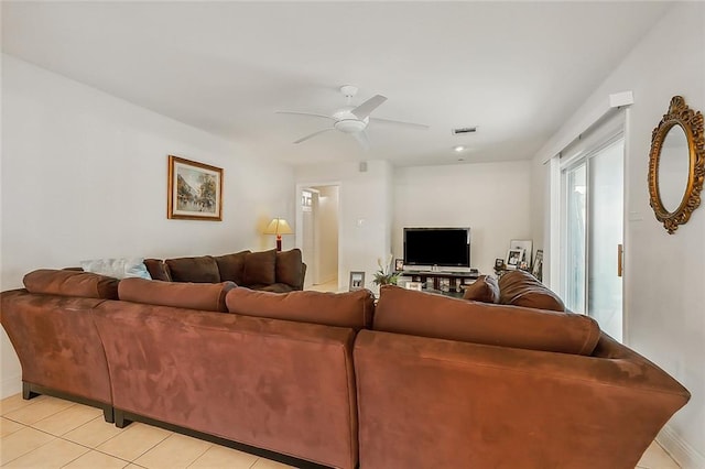 living room with light tile patterned floors, visible vents, baseboards, and a ceiling fan