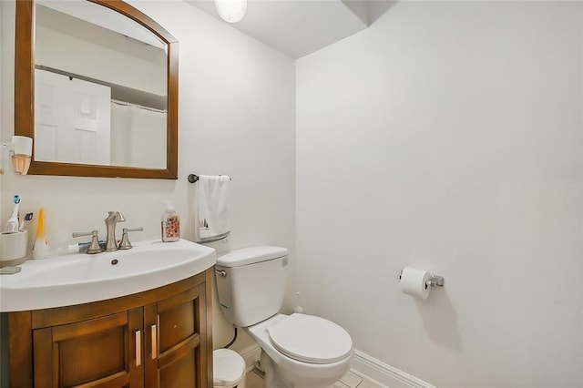 bathroom featuring tile patterned flooring, vanity, baseboards, and toilet