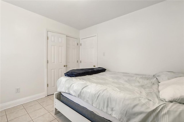bedroom featuring a closet, light tile patterned floors, and baseboards