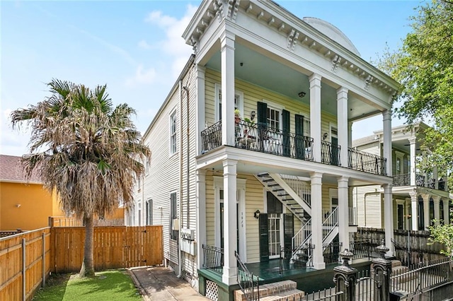 101012 Philip St, New Orleans, LA 70130 - view of front of home with a fenced backyard, a balcony, stairway, and covered porch