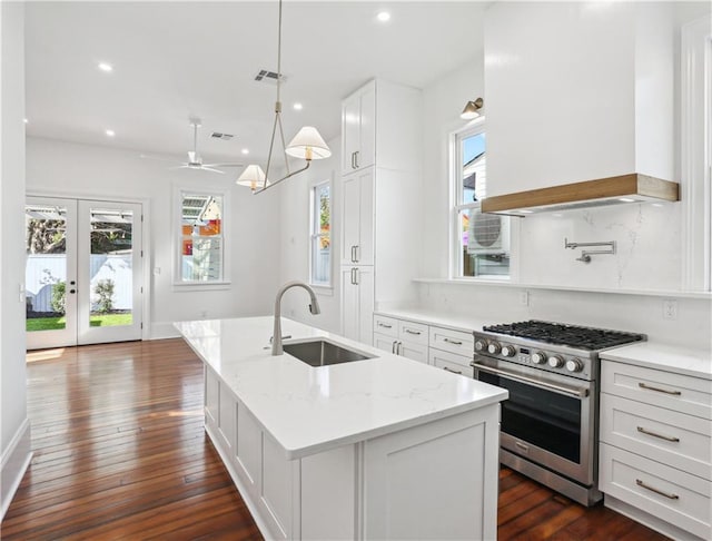 2623 Dauphine St, New Orleans, LA 70117 - kitchen with high end stove, an island with sink, recessed lighting, white cabinetry, and dark wood finished floors