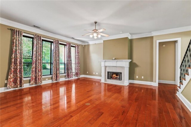 unfurnished living room with stairs, a fireplace, crown molding, and a ceiling fan