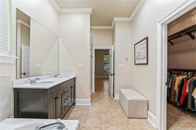 bathroom featuring a sink, ornamental molding, double vanity, a walk in closet, and tile patterned floors