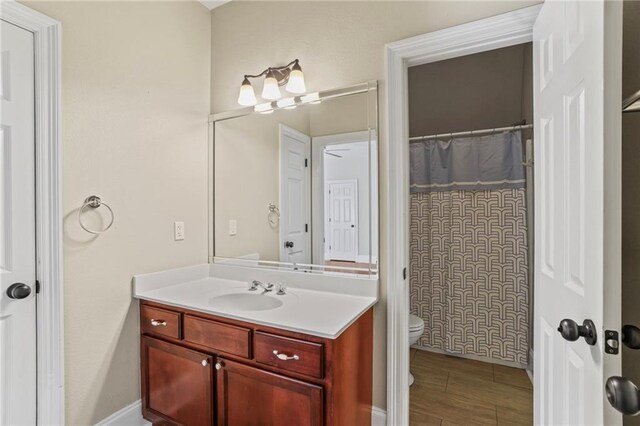 bathroom with toilet, vanity, a shower with curtain, and baseboards