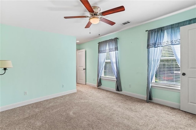 carpeted spare room featuring ceiling fan, baseboards, and visible vents