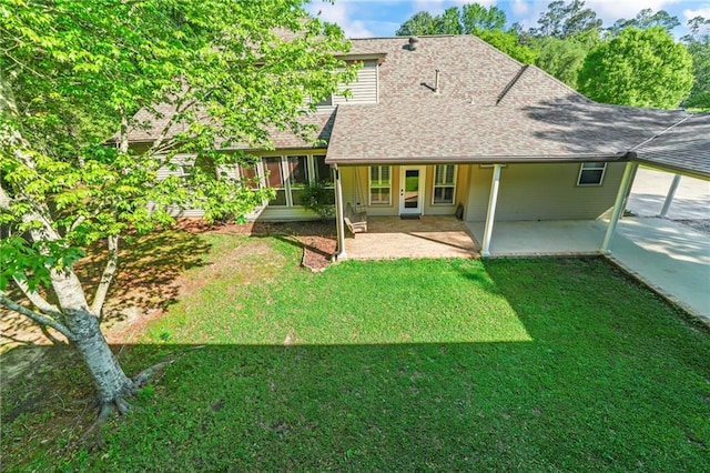 rear view of property with a patio, roof with shingles, and a lawn