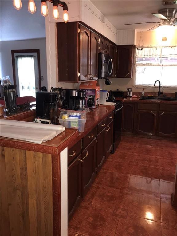 219 Queen Anne Dr, Slidell, LA 70460 - kitchen featuring ceiling fan, stove, stainless steel microwave, a sink, and dark countertops