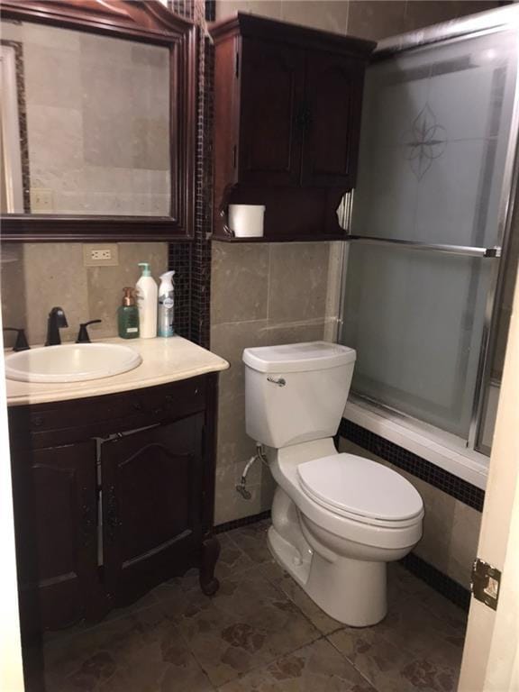 219 Queen Anne Dr, Slidell, LA 70460 - full bathroom featuring shower / bath combination with glass door, vanity, tile walls, and toilet