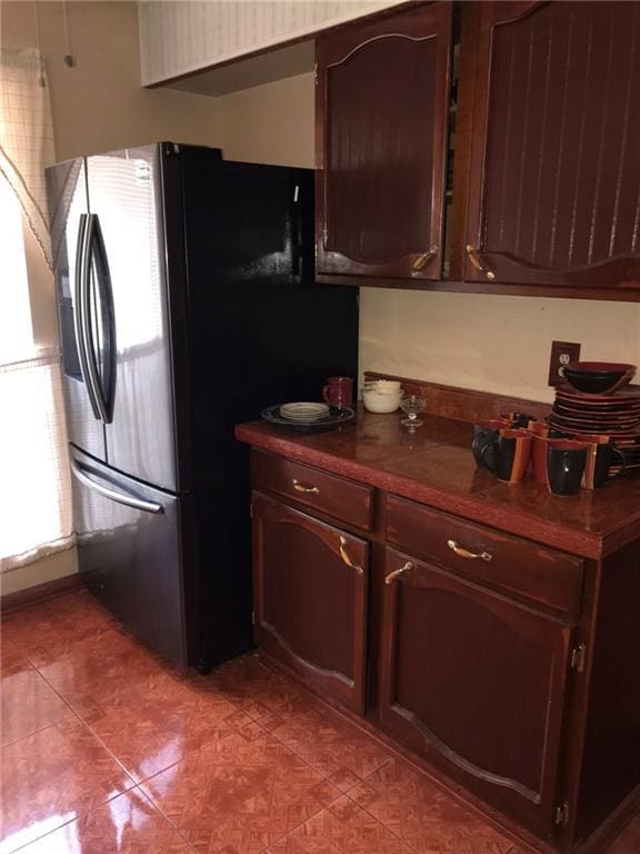 219 Queen Anne Dr, Slidell, LA 70460 - kitchen featuring light tile patterned floors, dark countertops, stainless steel fridge, and dark brown cabinets