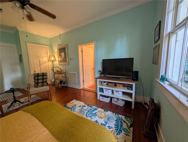 bedroom with wood finished floors, visible vents, ornamental molding, baseboards, and ceiling fan