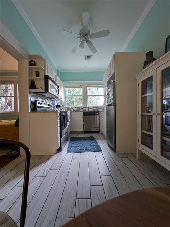 kitchen with light wood finished floors, visible vents, ornamental molding, appliances with stainless steel finishes, and ceiling fan
