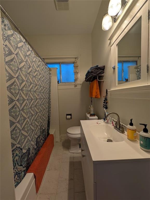 full bath with vanity, shower / bath combination with curtain, marble finish floor, toilet, and visible vents