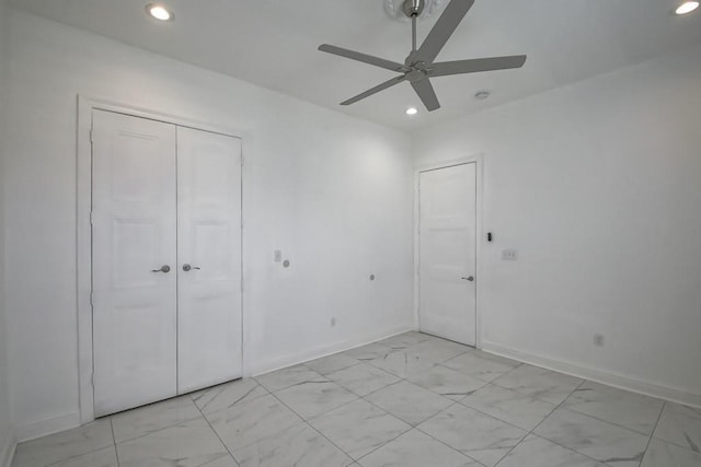unfurnished bedroom with a closet, baseboards, recessed lighting, and marble finish floor