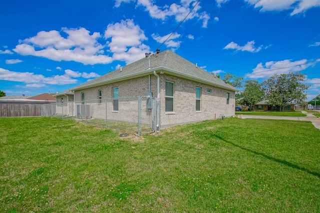 view of side of property featuring a yard, fence, and brick siding