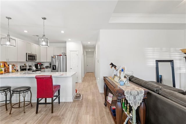 10735 Vienna St, New Orleans, LA 70126 - kitchen with open floor plan, light wood-type flooring, a breakfast bar, a peninsula, and stainless steel appliances