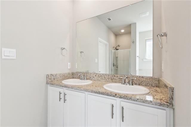 full bath featuring double vanity, visible vents, a sink, and a stall shower