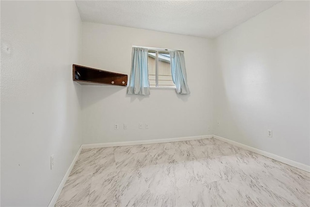 spare room featuring baseboards and a textured ceiling