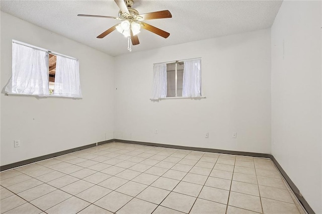 spare room with a textured ceiling, ceiling fan, and baseboards