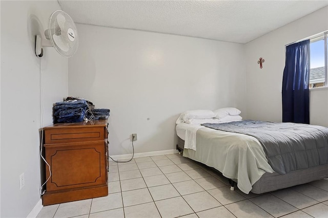 bedroom featuring light tile patterned floors, baseboards, and a textured ceiling
