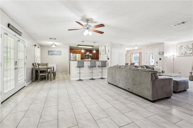 living room with visible vents, light tile patterned flooring, and ceiling fan