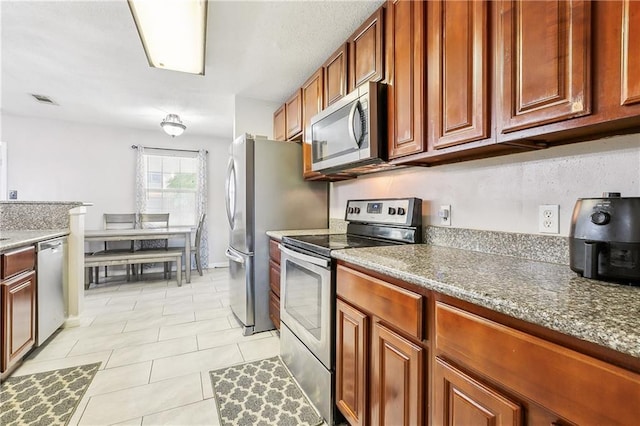 kitchen with brown cabinets, appliances with stainless steel finishes, light tile patterned floors, and visible vents