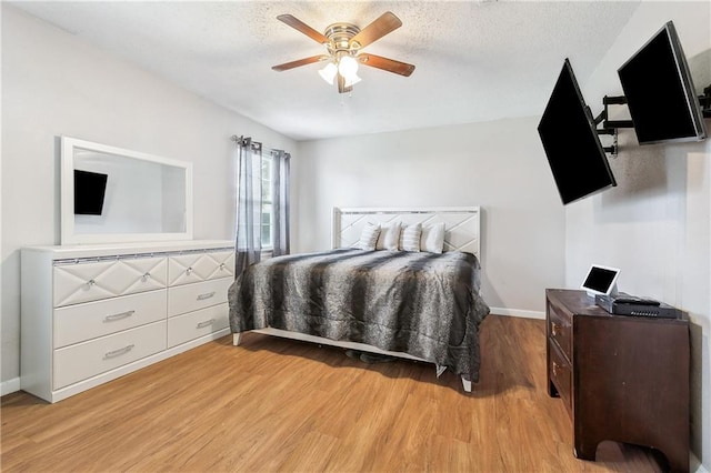 bedroom featuring baseboards, light wood finished floors, and a ceiling fan