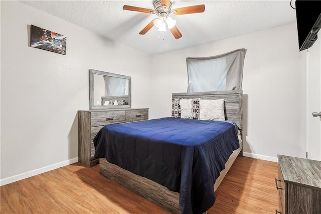 bedroom with light wood-style floors, baseboards, and a ceiling fan