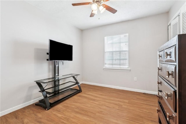 interior space featuring light wood finished floors, baseboards, a ceiling fan, and a healthy amount of sunlight