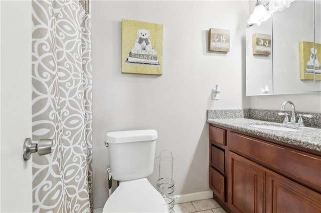 bathroom with toilet, vanity, baseboards, and tile patterned flooring