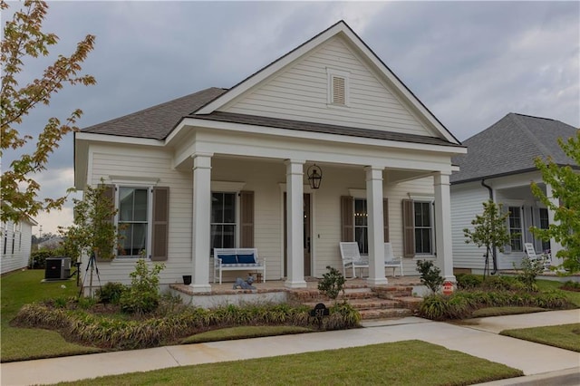 greek revival house with a porch, cooling unit, and a shingled roof