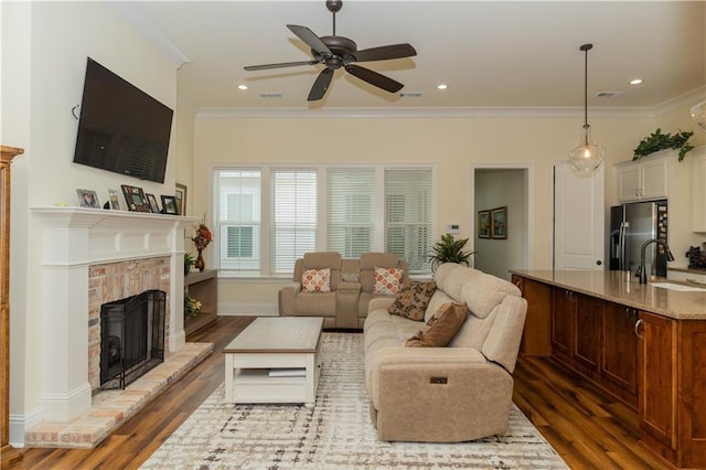 living room featuring a brick fireplace, ceiling fan, ornamental molding, and dark wood finished floors
