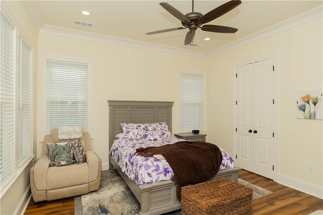 bedroom with crown molding, wood finished floors, baseboards, and visible vents