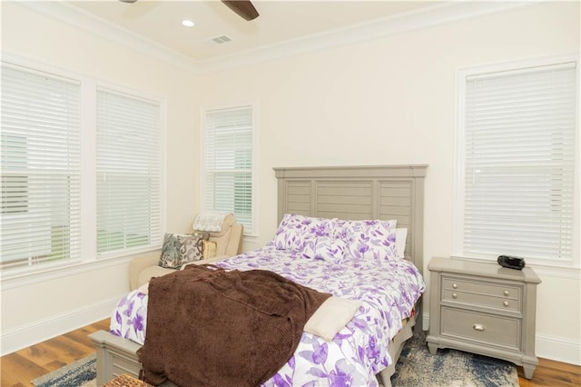 bedroom featuring wood finished floors, baseboards, ornamental molding, and visible vents