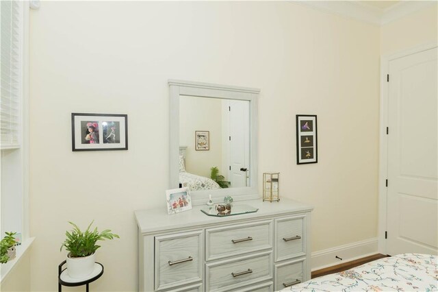bedroom featuring baseboards, crown molding, and wood finished floors