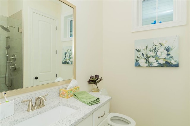 bathroom with tiled shower, vanity, and toilet