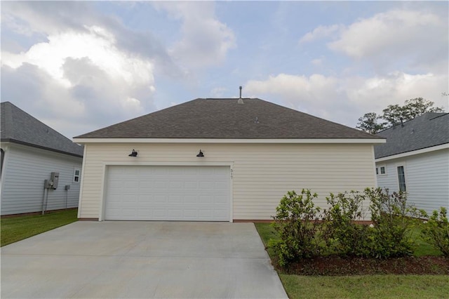 exterior space with roof with shingles, a garage, and concrete driveway