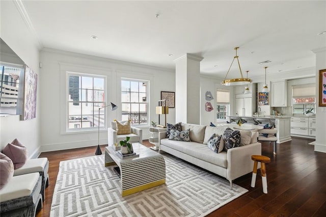 living room with dark wood-style floors, baseboards, ornamental molding, and visible vents