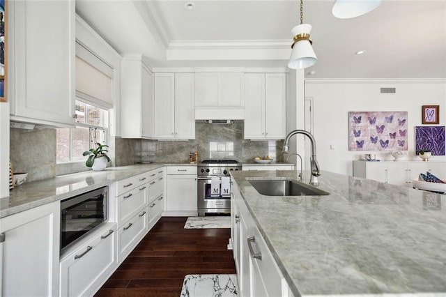 kitchen with a sink, ornamental molding, appliances with stainless steel finishes, and light stone counters